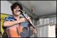 A person playing guitar and singing into a microphone

Description automatically generated with medium confidence