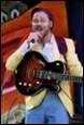A person holding a guitar and singing

Description automatically generated with medium confidence