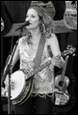 A person singing into a microphone and playing a banjo

Description automatically generated