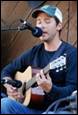 A person playing guitar and singing into microphone

Description automatically generated