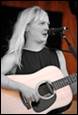 A person with long hair holding a guitar

Description automatically generated
