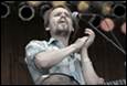 A person with his hands together on a microphone

Description automatically generated