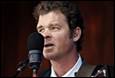 A person with a guitar and a microphone

Description automatically generated