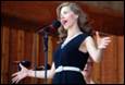 A person in a black dress speaking into a microphone

Description automatically generated
