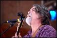 A person with a beard singing into a microphone

Description automatically generated