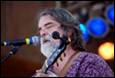 A person with a beard playing a guitar

Description automatically generated