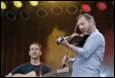 A person playing a violin and a person playing a guitar

Description automatically generated