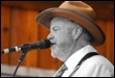 A person in a hat with a microphone

Description automatically generated