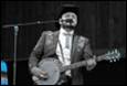 A person in a cowboy hat playing a banjo

Description automatically generated
