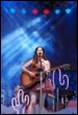 A person playing a guitar on a stage

Description automatically generated