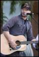 A person playing guitar and singing into a microphone

Description automatically generated