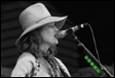 A person wearing a hat and singing into a microphone

Description automatically generated