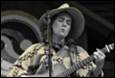 A person in a cowboy hat playing a guitar

Description automatically generated