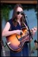 A person playing guitar and singing into a microphone

Description automatically generated