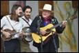 A person playing a guitar with a group of men behind him

Description automatically generated