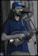 A person with a beard playing a guitar

Description automatically generated