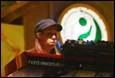 A person wearing a cap and standing behind a dj set

Description automatically generated