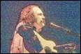 A person with a guitar and microphone

Description automatically generated