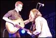 A person playing guitar with another person on stage

Description automatically generated with low confidence
