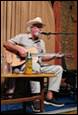 A person in a cowboy hat playing guitar

Description automatically generated