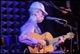 A person playing a guitar on stage

Description automatically generated