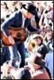 A person playing a guitar in front of a crowd

Description automatically generated with medium confidence