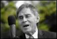 A person in a suit speaking into a microphone

Description automatically generated