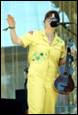 A person in yellow jumpsuit holding a guitar

Description automatically generated with medium confidence