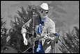A person playing guitar and wearing a cowboy hat

Description automatically generated
