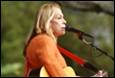 A person with a guitar and a microphone

Description automatically generated