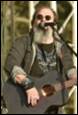 A person with a beard playing a guitar

Description automatically generated