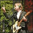 A person holding a guitar and pointing up

Description automatically generated