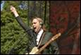 A person with his hand up and a guitar

Description automatically generated