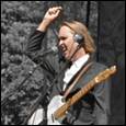 A person holding a guitar and raising his hand

Description automatically generated