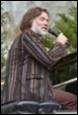 A person with a beard speaking into a microphone

Description automatically generated