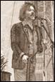 A person holding a guitar and standing next to a microphone

Description automatically generated