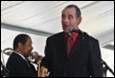 A person in a suit and tie speaking into a microphone

Description automatically generated with low confidence