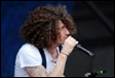 A person with curly hair singing into a microphone

Description automatically generated