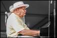 A person in a white hat playing a piano

Description automatically generated with medium confidence