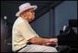 A person in a hat playing a piano

Description automatically generated with low confidence