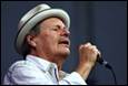 A person wearing a hat and holding a microphone

Description automatically generated with medium confidence