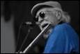 A person with a hat and sunglasses singing into a microphone

Description automatically generated with low confidence
