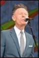 A person in a suit singing into a microphone

Description automatically generated