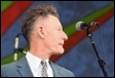 A person in a suit and tie speaking into a microphone

Description automatically generated with medium confidence