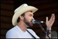 A person wearing a cowboy hat and holding a microphone

Description automatically generated with medium confidence