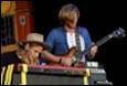 A person playing a guitar with another person behind him

Description automatically generated with low confidence