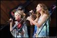 A group of women singing into microphones

Description automatically generated