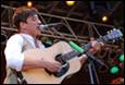 A person playing guitar and singing into microphones

Description automatically generated