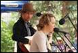 A person playing guitar and singing into microphones

Description automatically generated