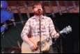 A person playing guitar on stage

Description automatically generated
